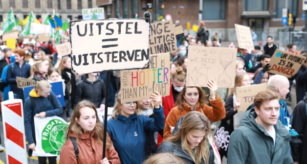Protesterende mensen op een klimaatmars. In het midden staat een bord met Uitstel = uitsterven. GroenLinks-PvdA wil fossiele subsidies stoppen.
