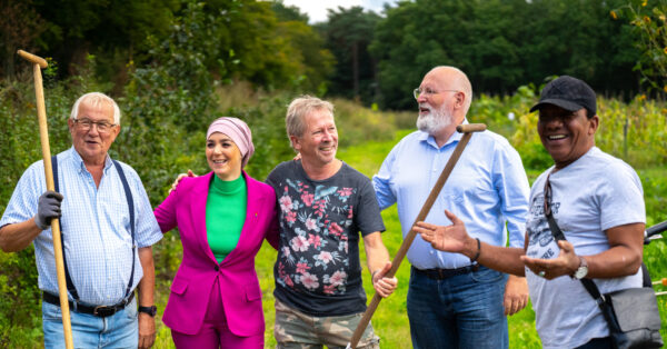 Frans Timmermans en Esmah Lahlah op campagne tour. Ze staan lachend buiten omarmd met drie mensen die ze tijdens de campagne ontmoet hebben.